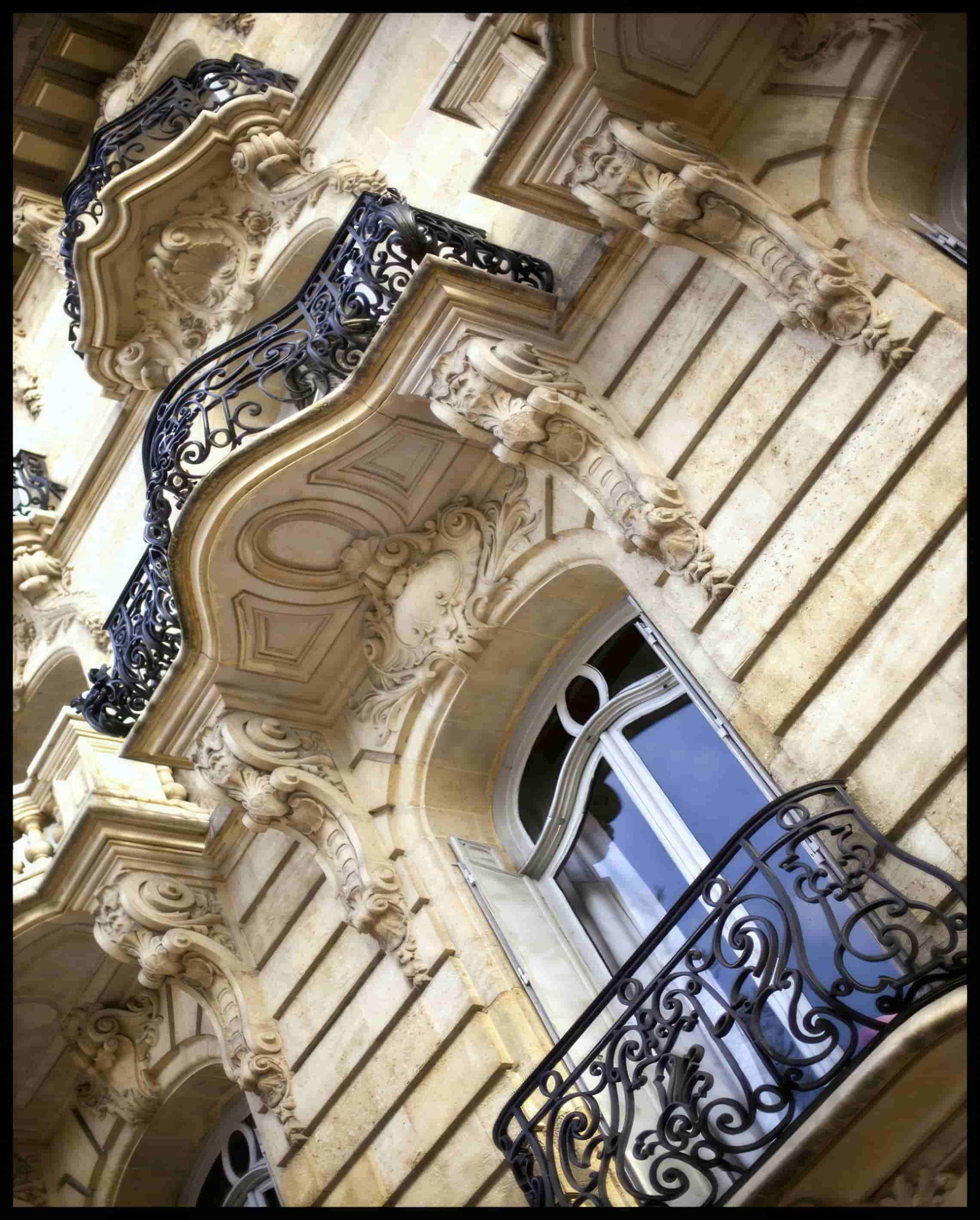 Ein Leinwandbild von einer kunstvoll verzierten Fassade mit Balkonen in Paris.