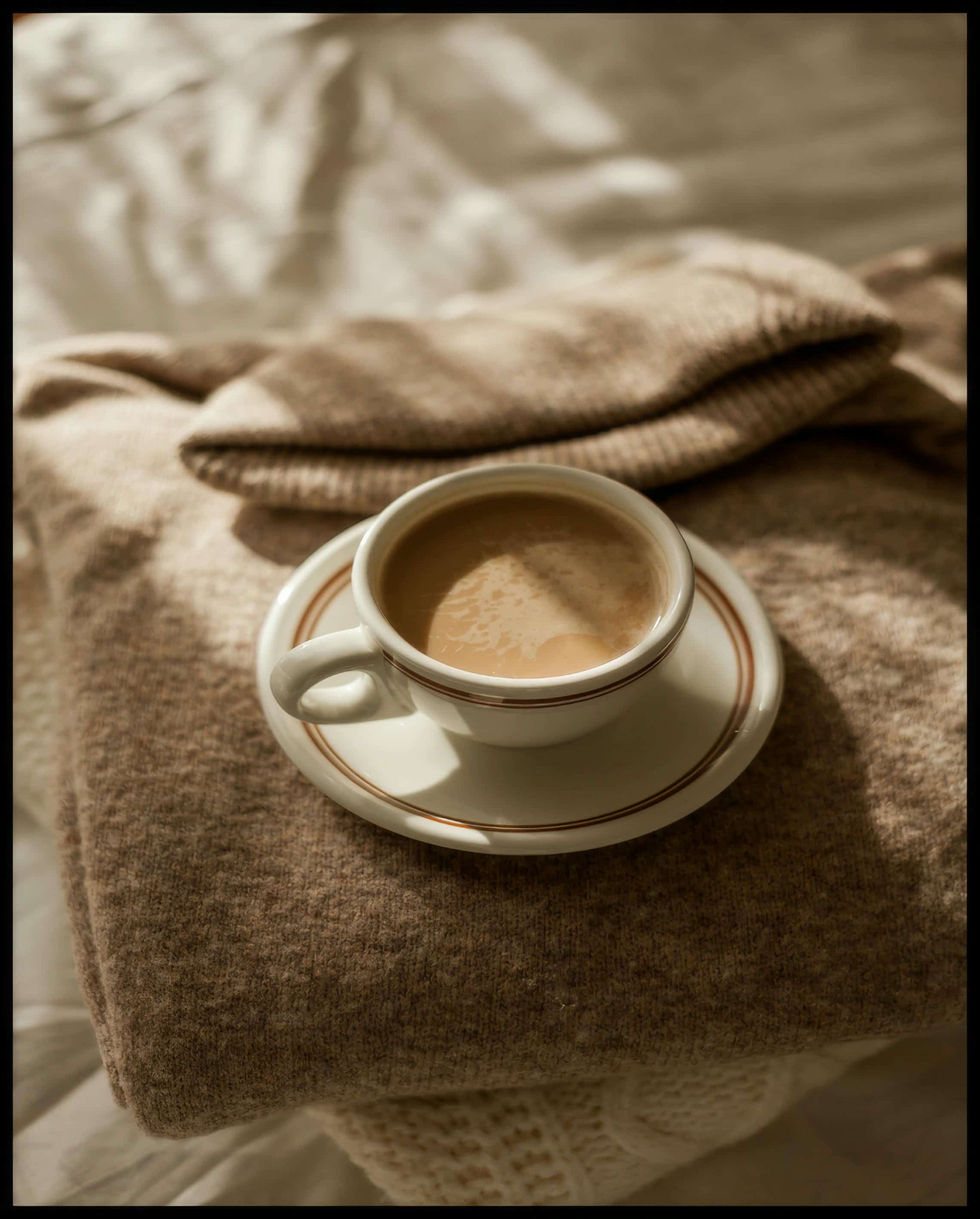 Ein Leinwandbild von einer Tasse Kaffee auf einem gemütlichen, beigen Pullover.