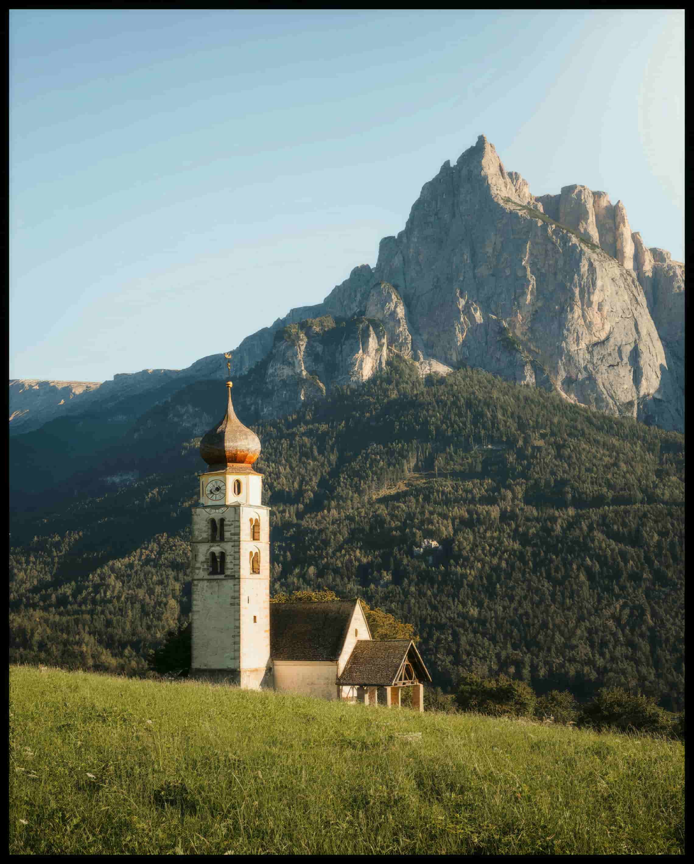 Leinwandbild von einer Kirche am Abhang eines Berges in den Dolomiten.
