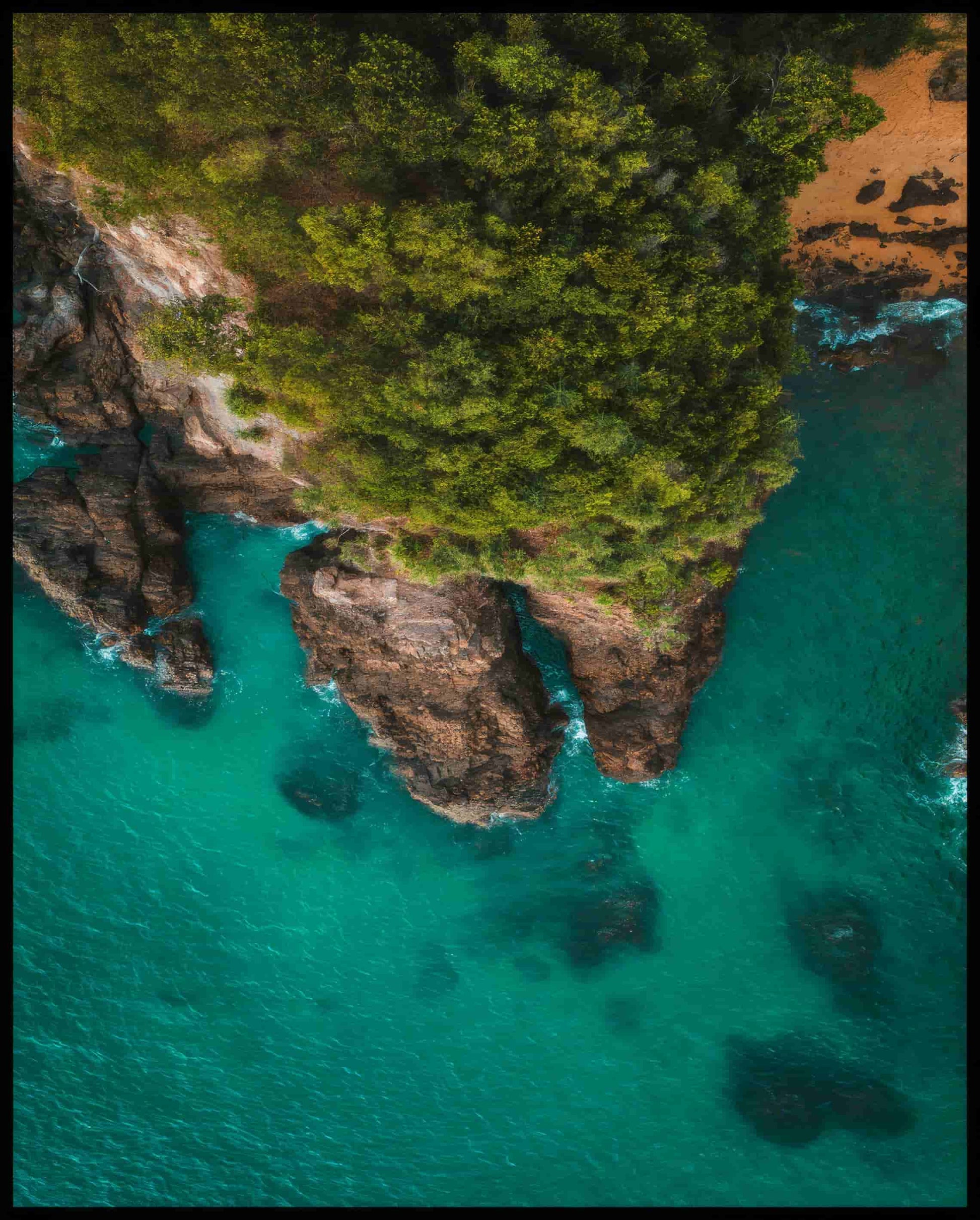 Leinwandbild von einer steilen, bewachsenen Klippe und blauem Meer.