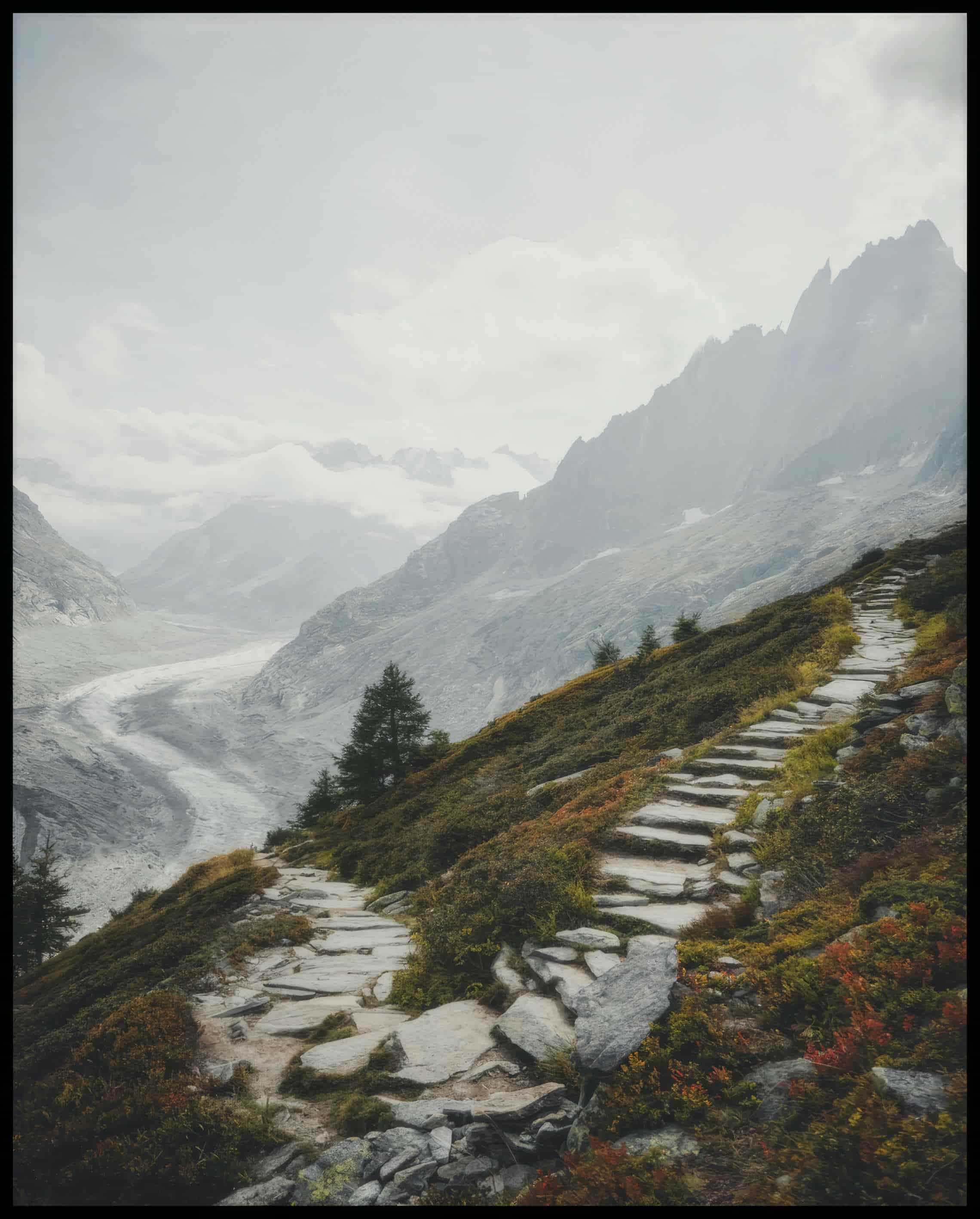 Leinwandbild von einem Wanderweg aus steinernen Treppen inmitten einer Berglandschaft.