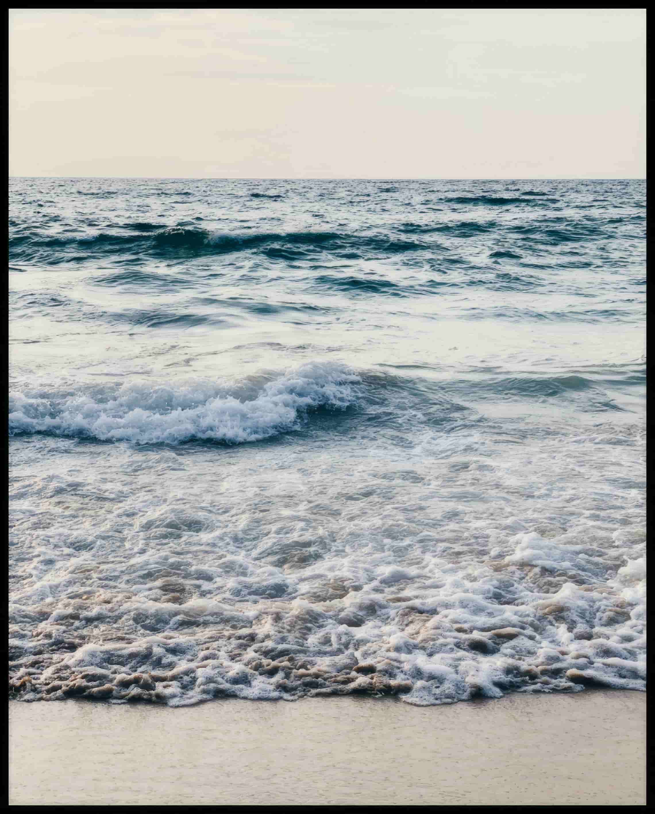 Leinwandbild von schaumigen Wellen am Strand.