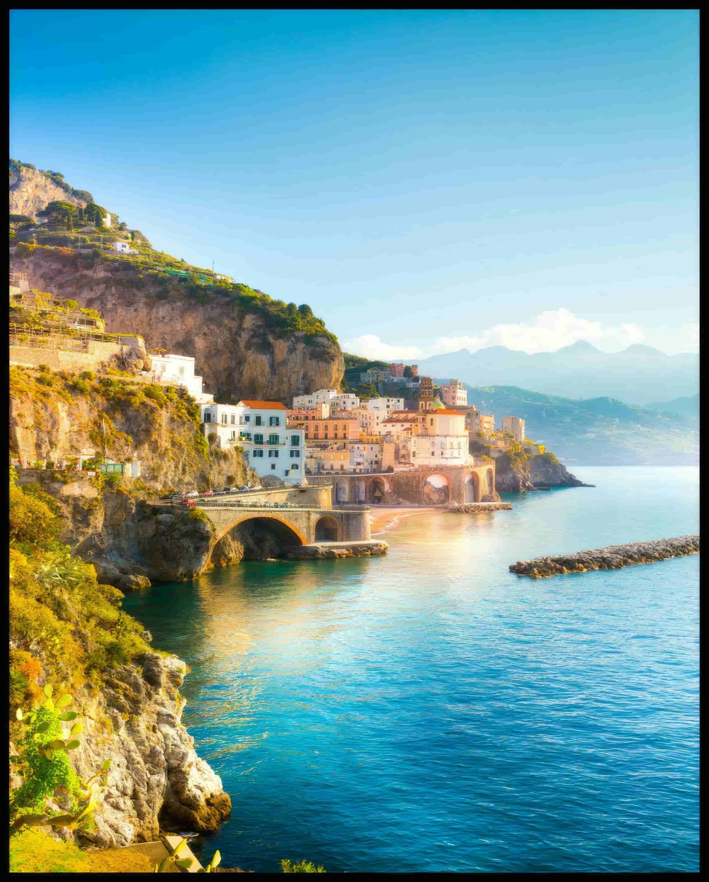 Ein Poster von einer Küstenstadt an der Amalfiküste in Italien, mit Häusern, die an steilen Klippen über dem türkisblauen Meer thronen.