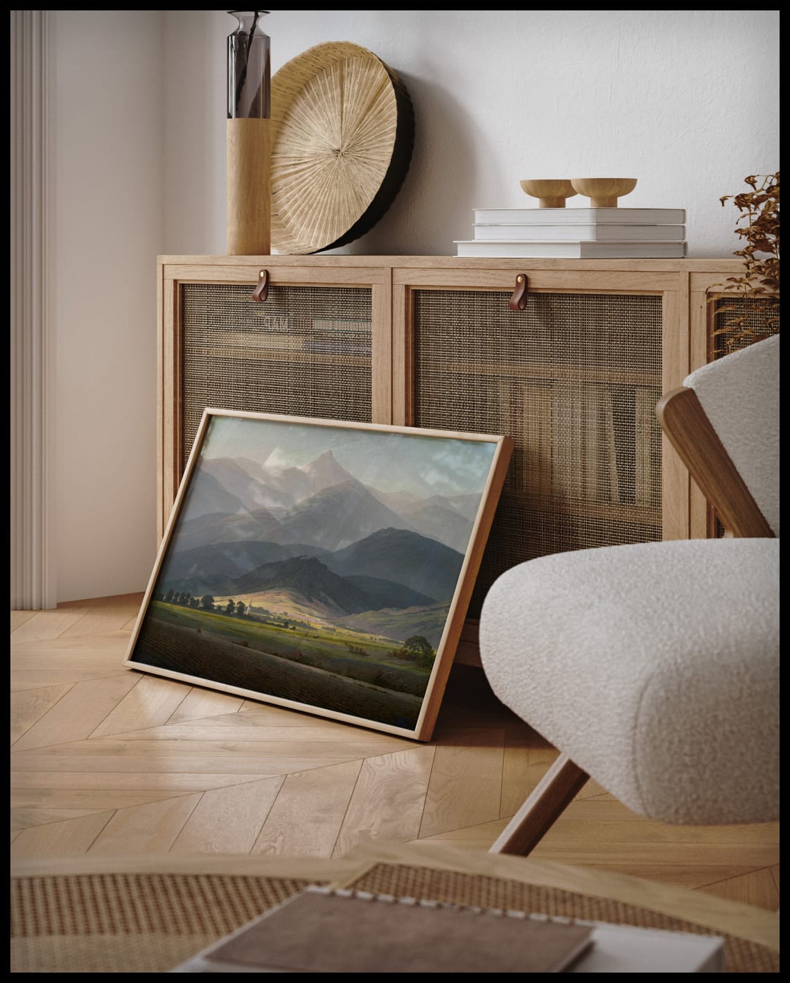 Ein gerahmter Kunstdruck von einer weitläufigen Berglandschaft mit vielen Äckern und Wiesen im Vordergrund, an einer Holzkommode angelehnt und stehend auf dem Holzboden