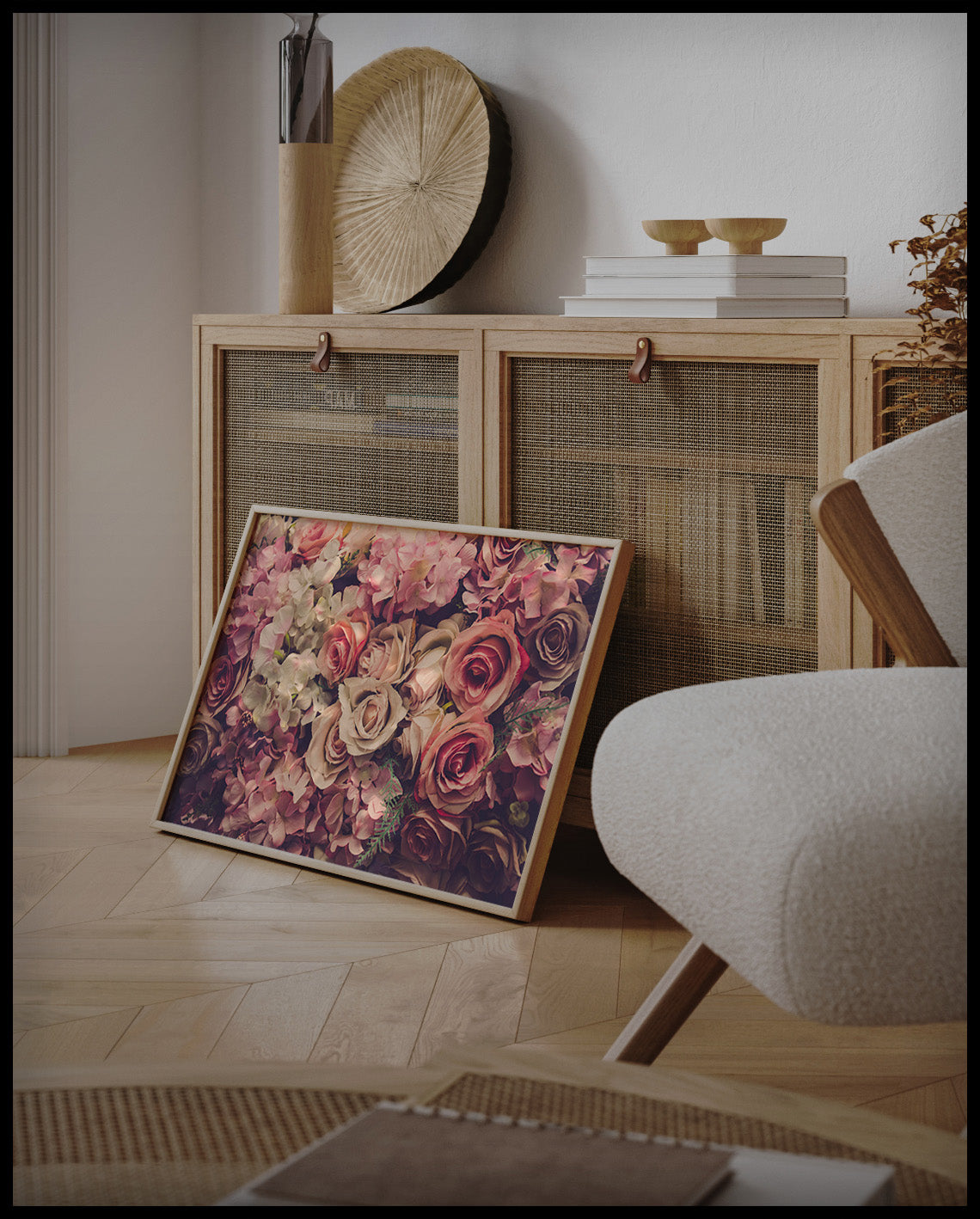 Ein gerahmtes Poster von einer Fülle rosa Blumen in einem üppigen Blumenstrauß, an einer Holzkommode angelehnt und stehend auf dem Holzboden