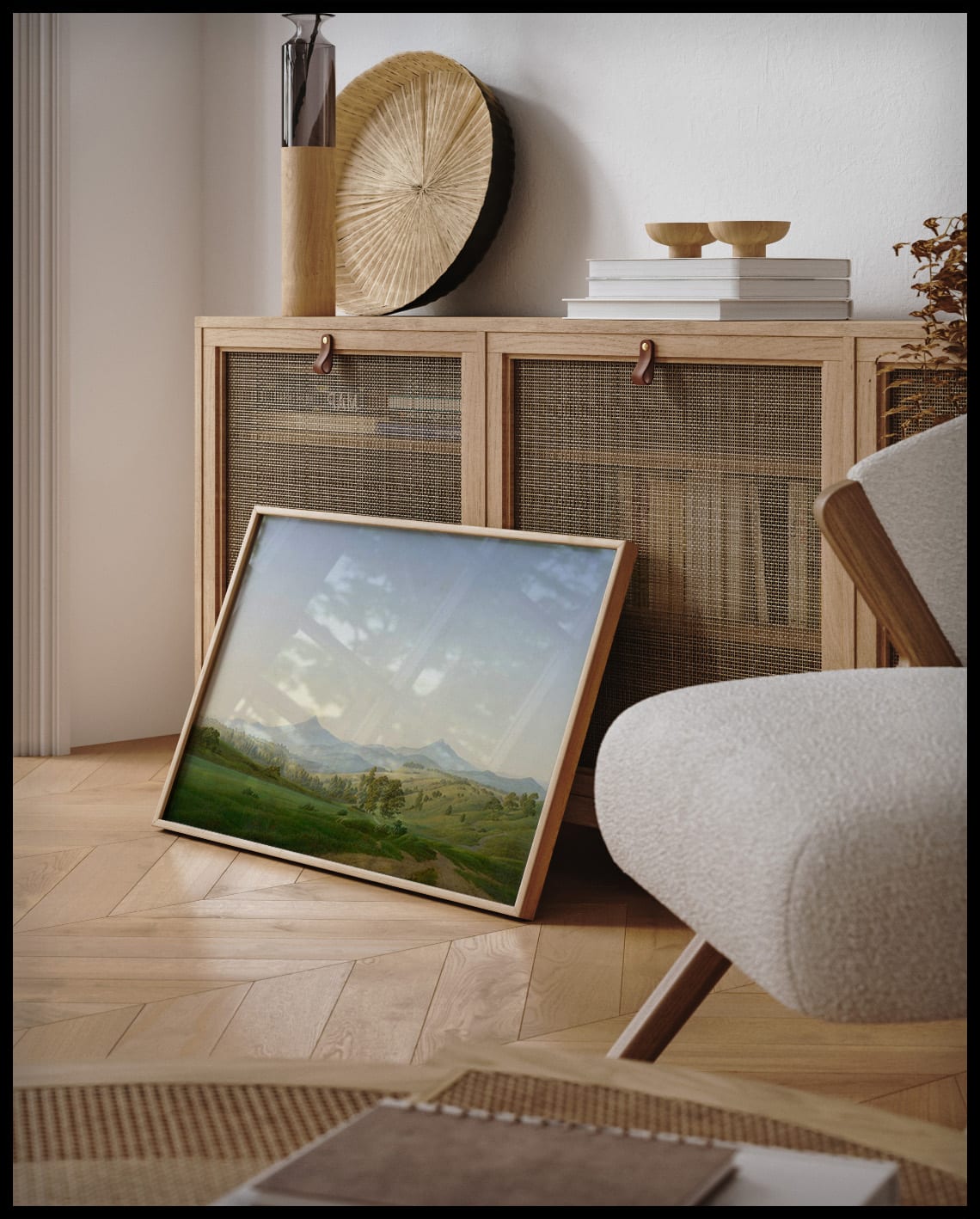Ein gerahmter Kunstdruck von einer weiten Landschaft mit hügeligen Wiesen und einigen Bäumen, an einer Holzkommode angelehnt und stehend auf dem Holzboden