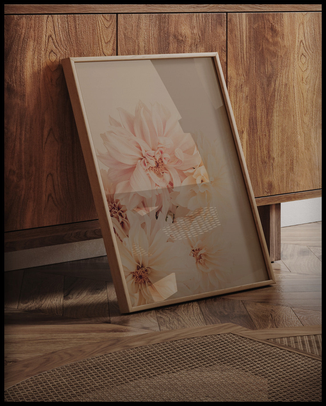 Ein gerahmtes Poster von zarten, pastellfarbenen Dahlienblüten, an einer Holzkommode angelehnt und stehend auf dem Holzboden