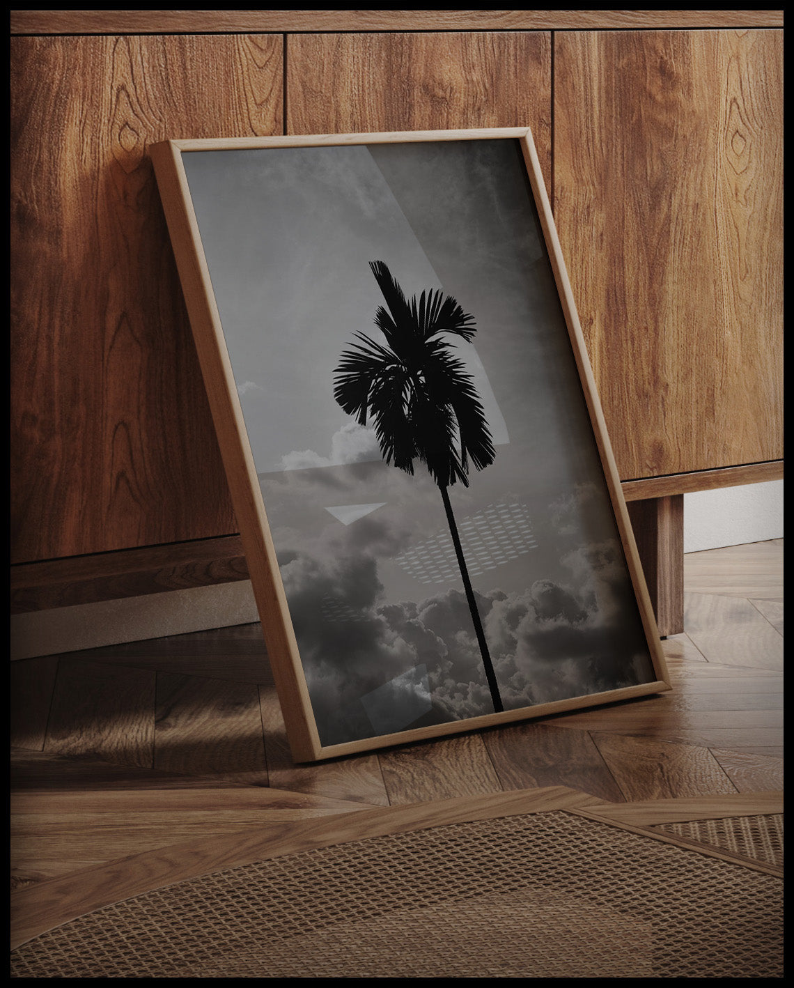 Ein gerahmtes Poster von einer einsamen Palme vor bewölktem Himmel in Schwarz-Weiß, an einer Holzkommode angelehnt und stehend auf dem Holzboden