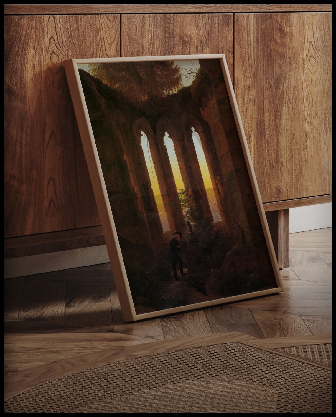 Ein gerahmter Kunstdruck einer verlassenen Ruine mit Sonnenuntergang im Hintergrund, an einer Holzkommode angelehnt und stehend auf dem Holzboden