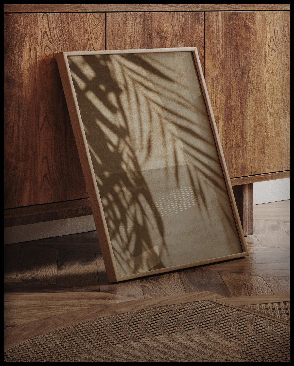 Ein gerahmtes Poster vom Schatten einzelner Palmenblätter auf einer beigefarbenen Häuserfassade, an einer Holzkommode angelehnt und stehend auf dem Holzboden