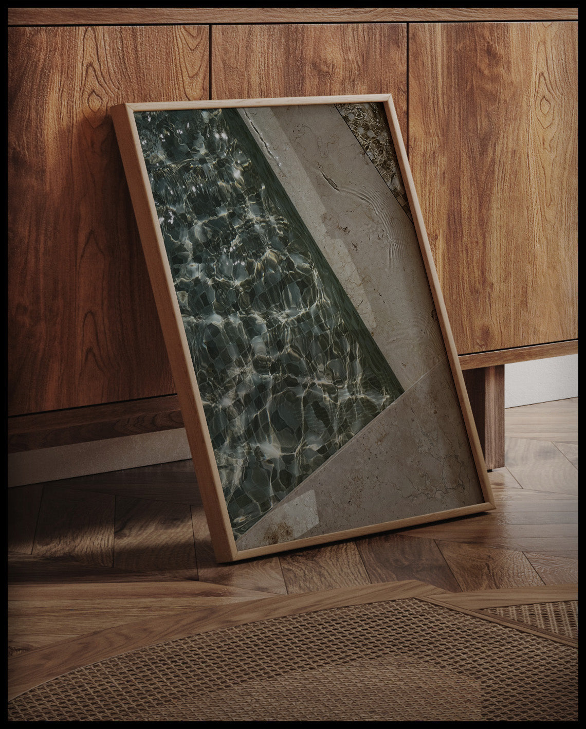 Ein gerahmtes Poster von einem Swimming Pool aus Marmor mit einem Mosaikmuster auf dem Beckengrund, an einer Holzkommode angelehnt und stehend auf dem Holzboden