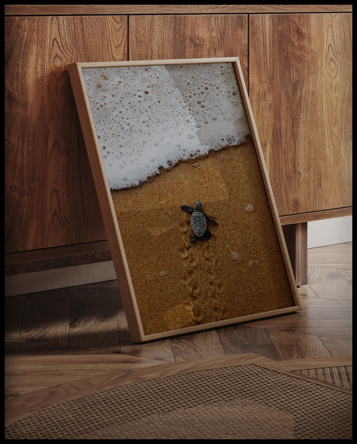 Ein gerahmtes Poster von einer Baby Schildkröte am Strand, die auf dem Weg zum Wasser ist, an einer Holzkommode angelehnt und stehend auf dem Holzboden