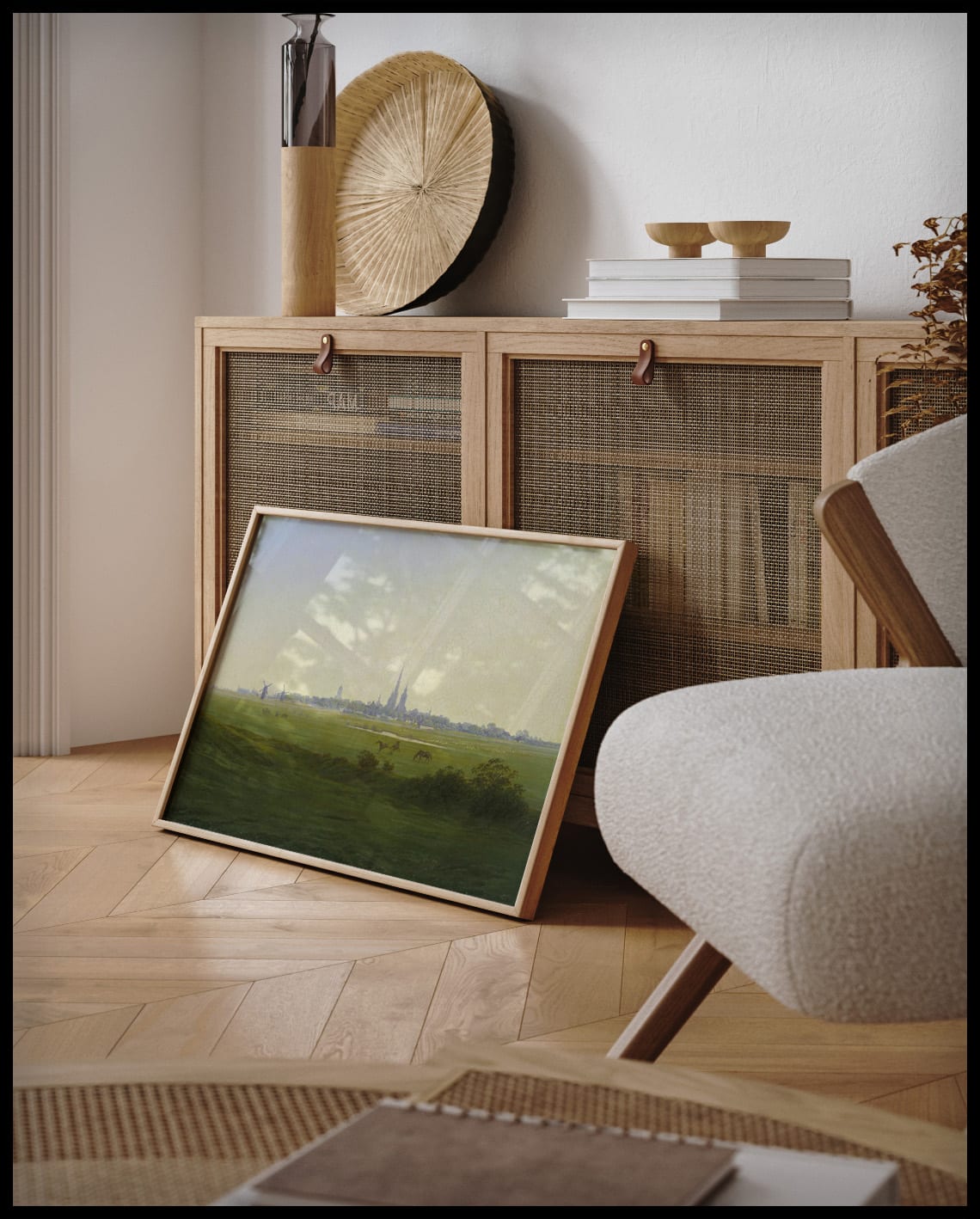 Ein gerahmter Kunstdruck von saftigen Wiesen und der Stadt Greifswald, die weit im Hintergrund liegt, an einer Holzkommode angelehnt und stehend auf dem Holzboden