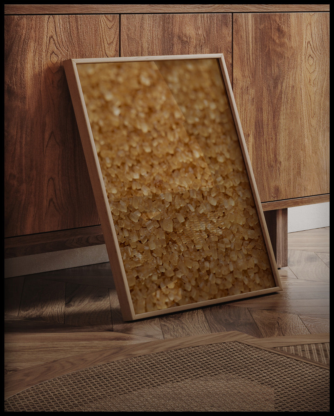 Ein gerahmtes Poster von einer Nahaufnahme von goldenen Zuckerpartikeln, an einer Holzkommode angelehnt und stehend auf dem Holzboden