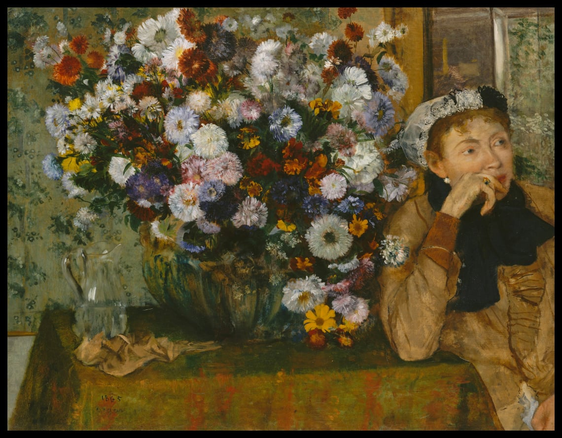 Une femme assise à côté d'un vase de fleurs
