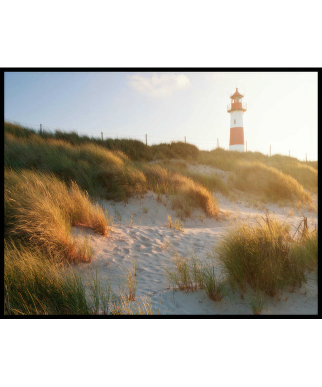 Ein Poster von einem Leuchtturm auf Sylt, der hinter grasbedeckten Dünen hervorschaut.