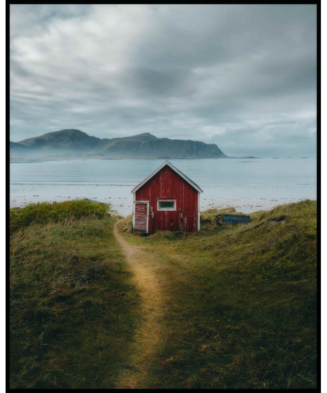 Ein Poster von einem kleinen roten Haus am Seeufer mit Bergen im Hintergrund.
