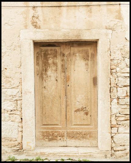 Ein Poster von einer alten, verwitterten Holztür in einer Steinmauer.