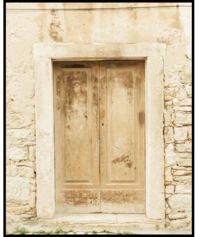 Ein Poster von einer alten, verwitterten Holztür in einer Steinmauer.