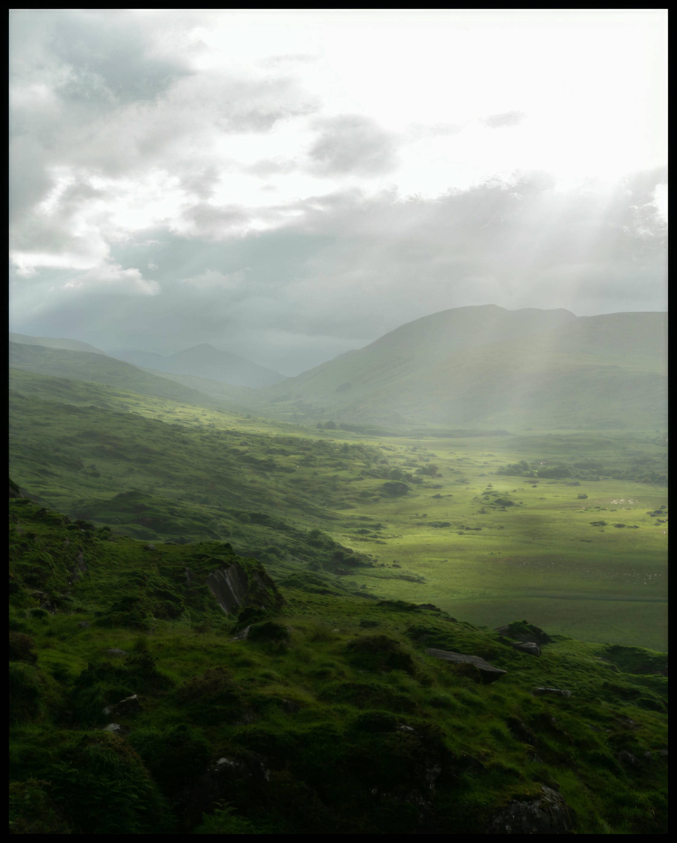 Ein Poster von einer grünen Landschaft in Irland mit Sonnenstrahlen.