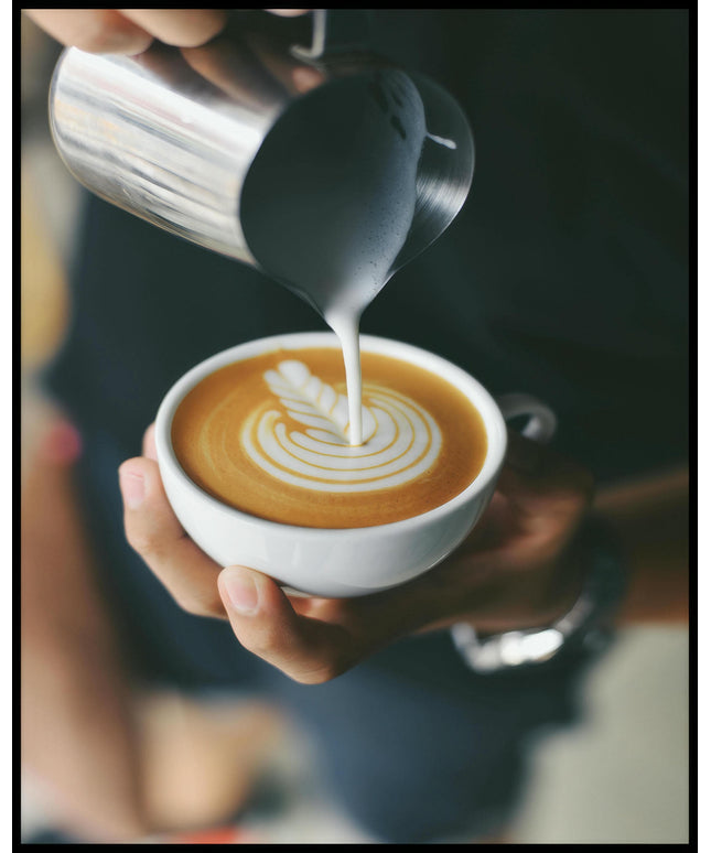 Ein Poster von einem Barista, der kunstvoll Milch in eine Tasse Kaffee gießt und ein Muster kreiert.