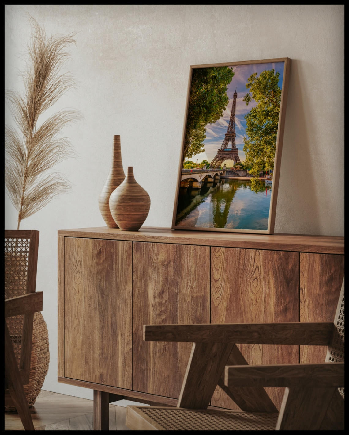 Ein gerahmtes Poster vom Eiffelturm der sich im Wasser spiegelt, auf einer Holzkommode an die Wand angelehnt