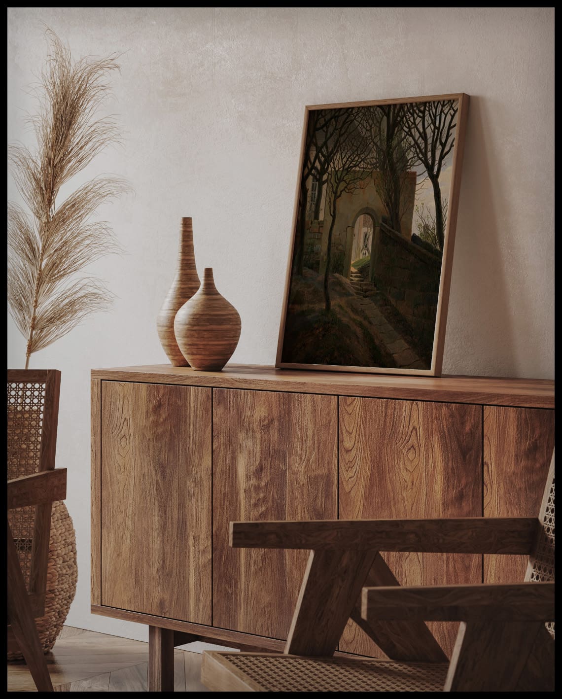 Ein gerahmter Kunstdruck mit einer Pforte und kahlen Bäumen, stehend auf einer Holzkommode und an die Wand gelehnt