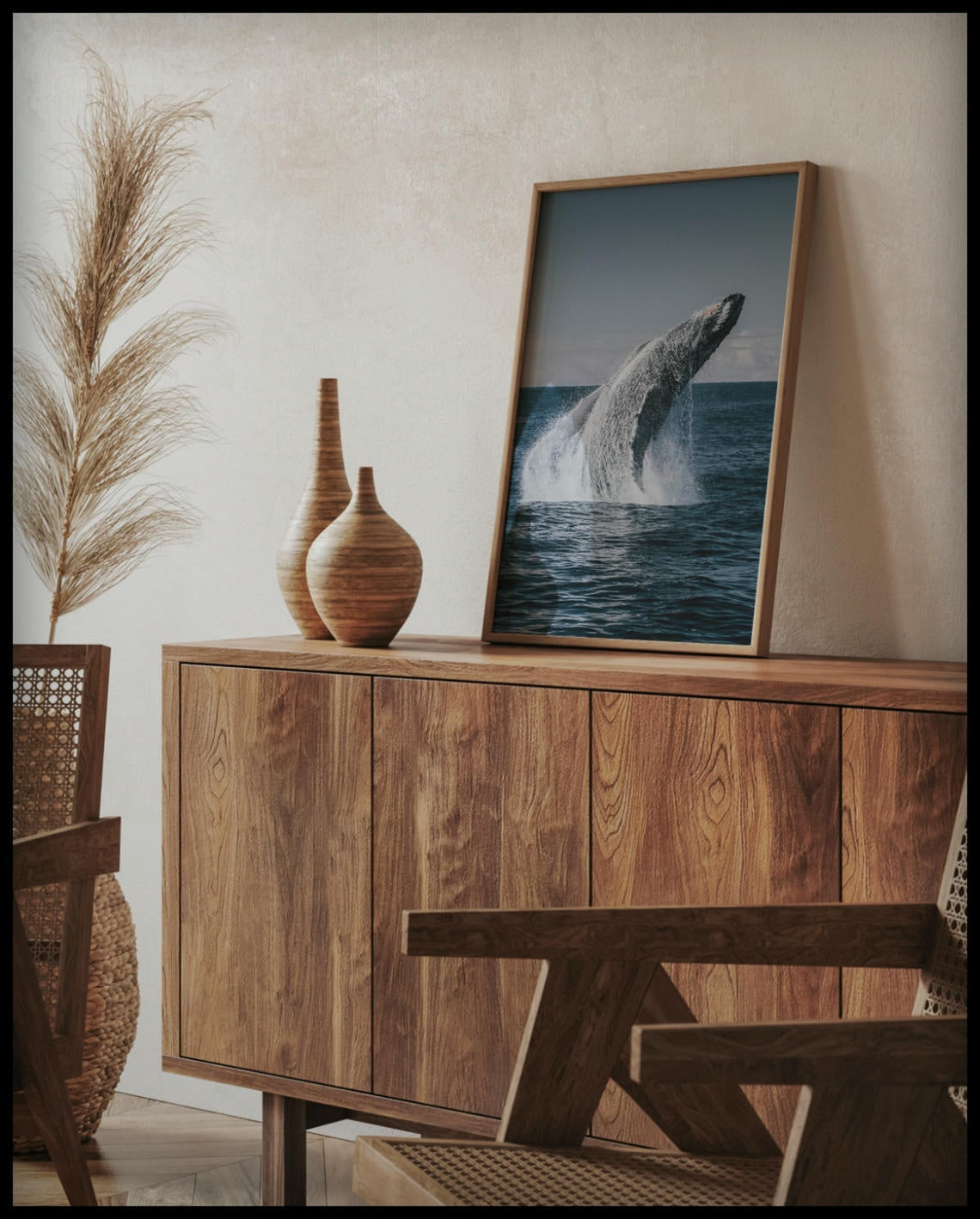 Ein gerahmtes Poster von einem Buckelwal der aus dem Meer heraus springt, auf einer Holzkommode an die Wand angelehnt