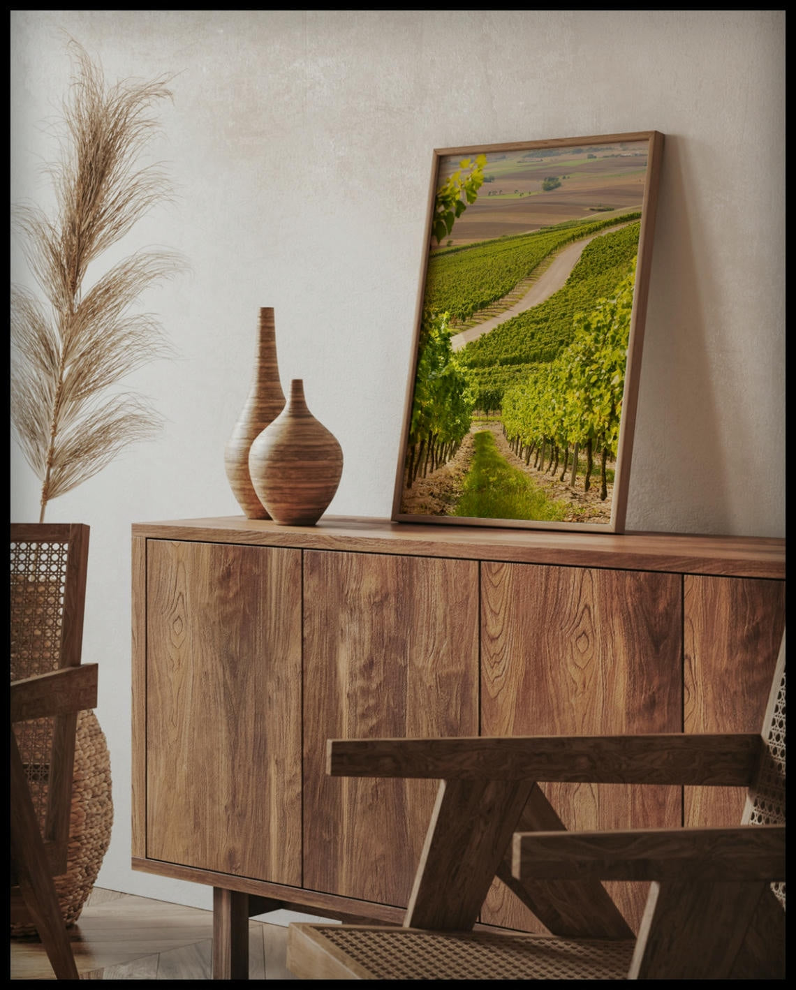 Ein gerahmtes Poster von einer Straße, die durch hellgrüne Weinberge führt, auf einer Holzkommode an die Wand angelehnt