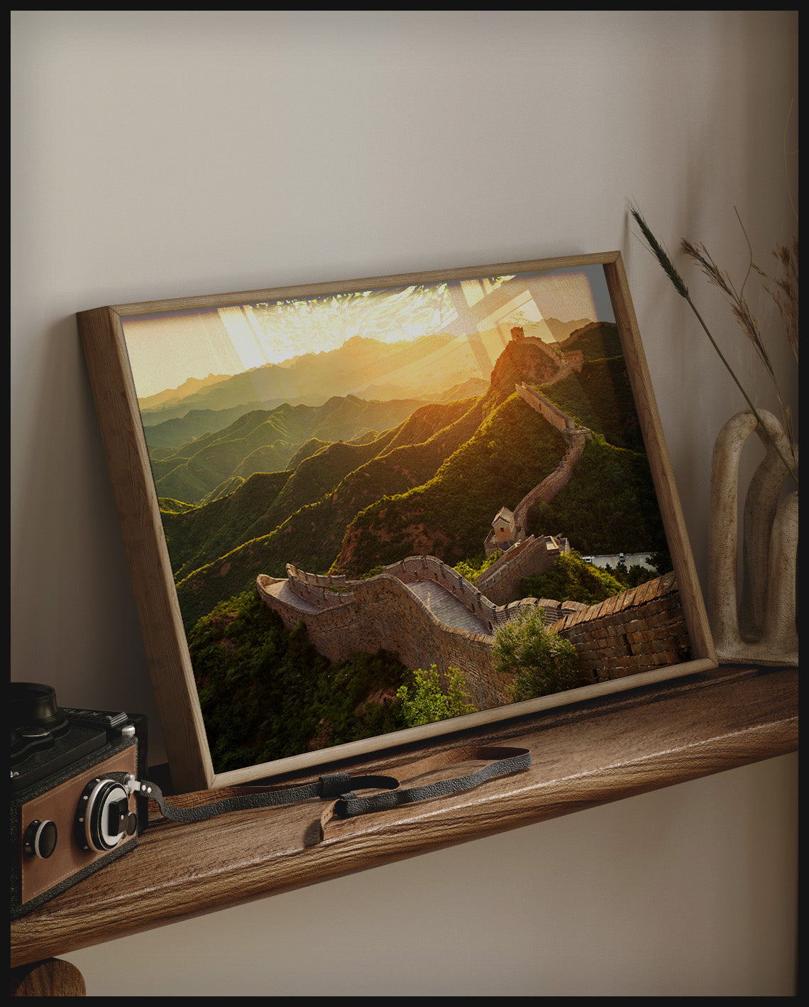 Ein gerahmtes Poster von der chinesischen Mauer im Sonnenuntergang, auf einem Holzregal an die Wand angelehnt