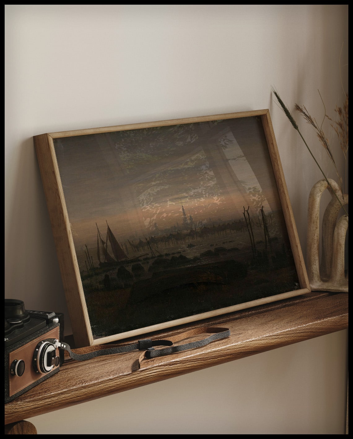 Ein gerahmter Kunstdruck von einer düsteren Flusslandschaft im Mondschein bei Greifswald, auf einem Holzregal an die Wand angelehnt