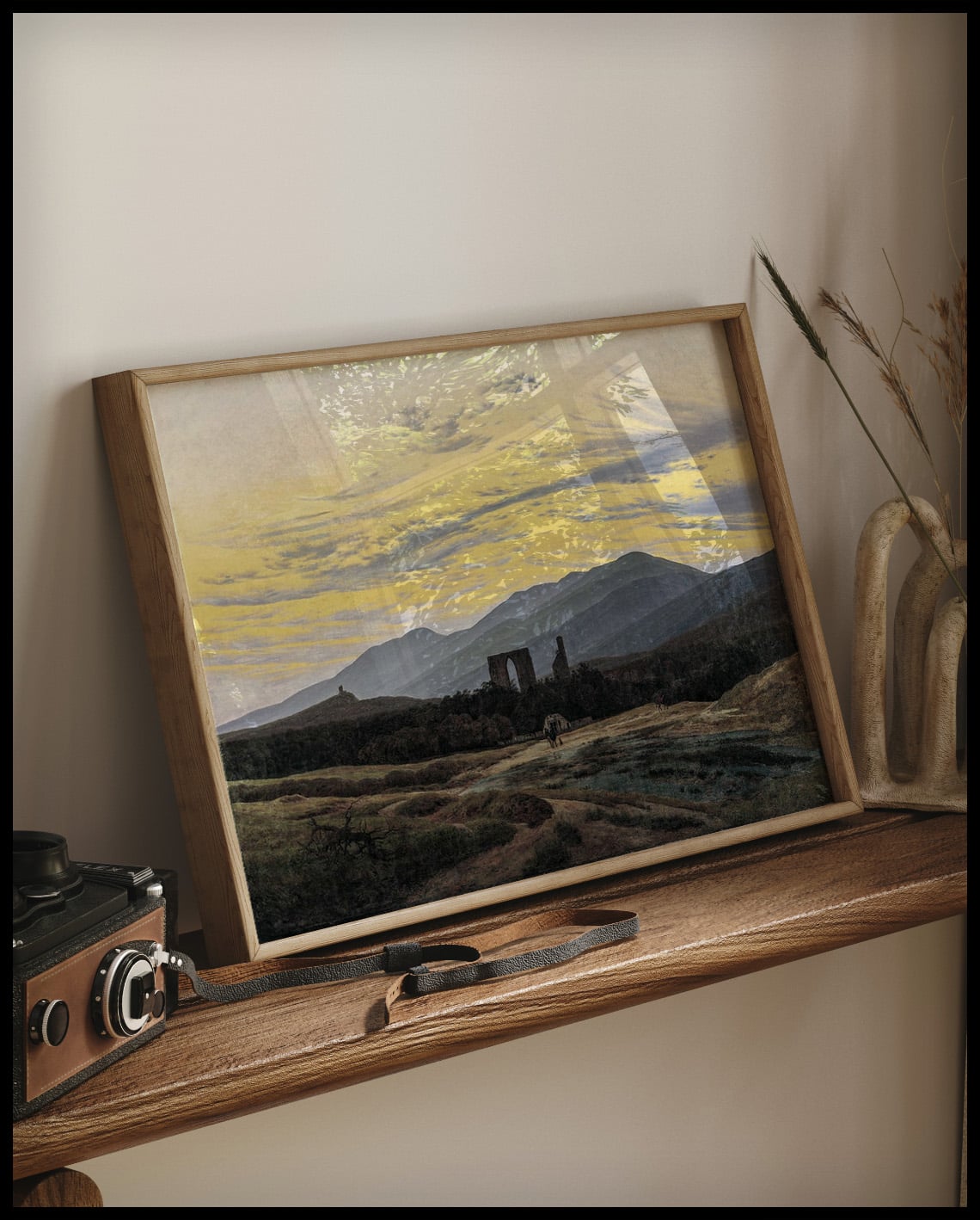 Ein gerahmter Kunstdruck von einer alten Ruine inmitten einer weiten Landschaft im Riesengebirge, auf einem Holzregal an die Wand angelehnt