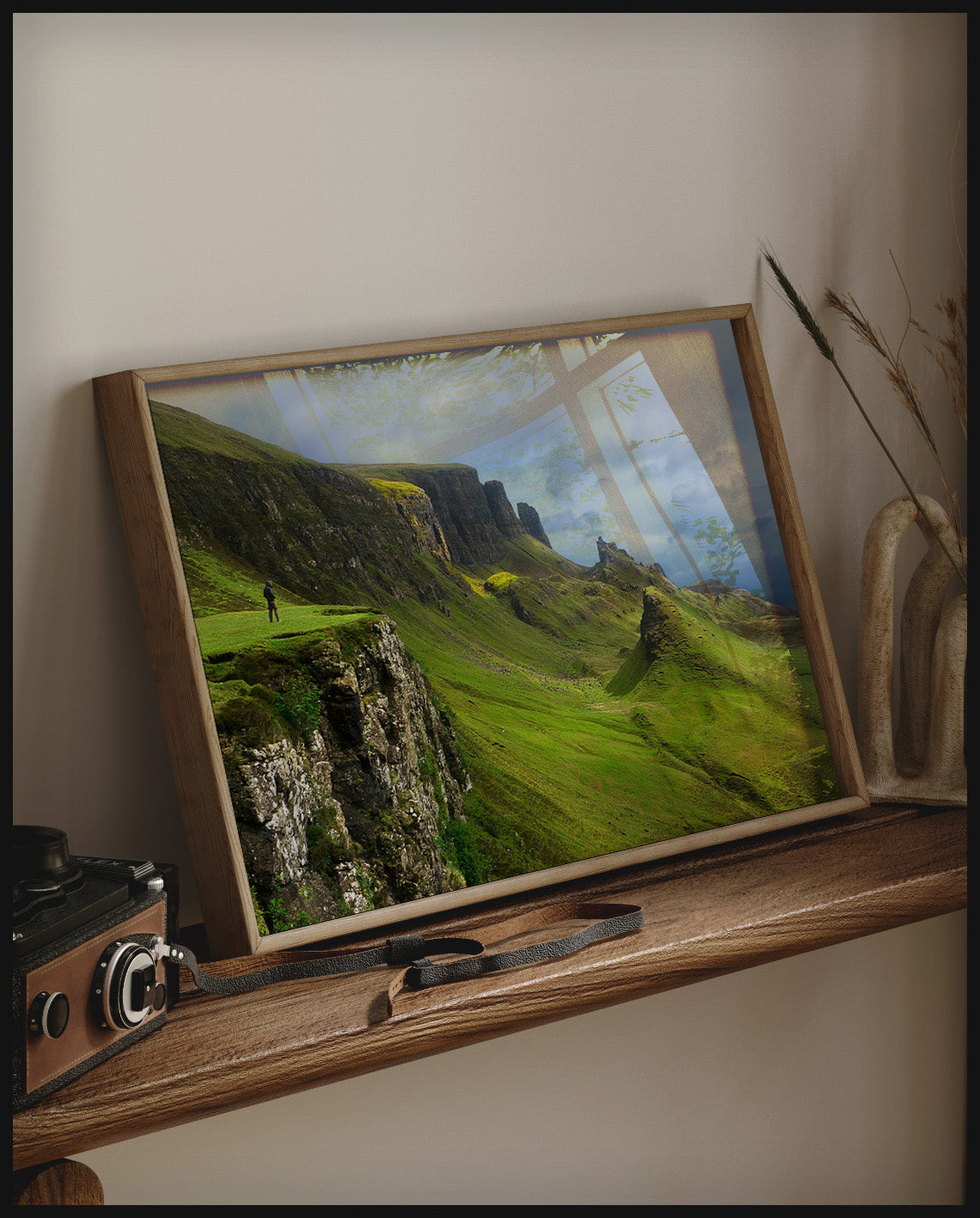 Ein gerahmtes Poster von grasbewachsenen Bergformationen auf der schottischen Insel Skye, auf einem Holzregal an die Wand angelehnt