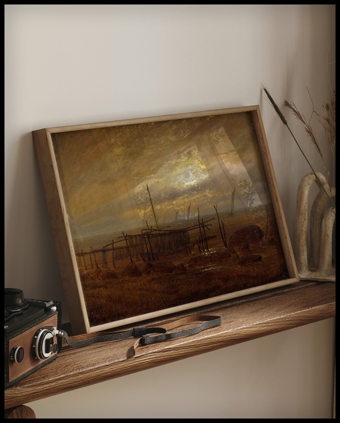 Ein gerahmter Kunstdruck von einer Küstenlandschaft im Mondschein, auf einem Holzregal an die Wand angelehnt