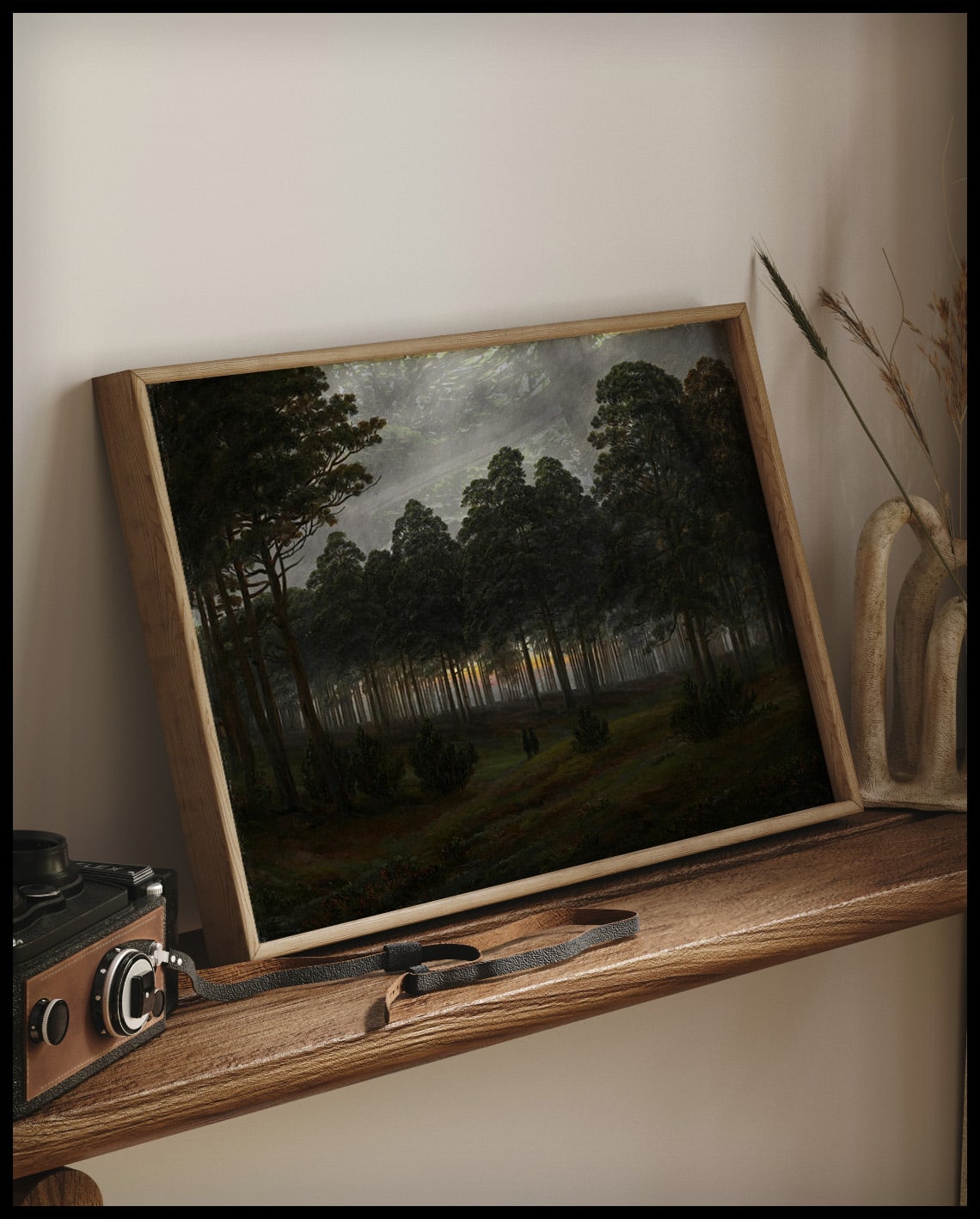 Ein Kunstdruck von einer Lichtung im Wald am Abend, auf einem Holzregal an die Wand angelehnt