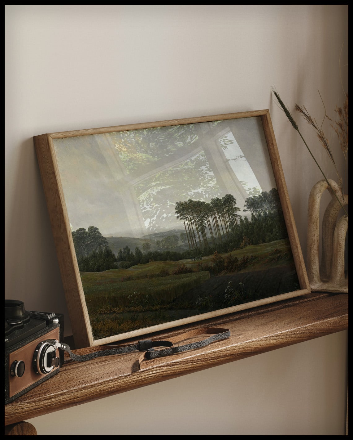 Ein gerahmter Kunstdruck von einer weiten, Landschaft am Nachmittag, auf einem Holzregal an die Wand angelehnt