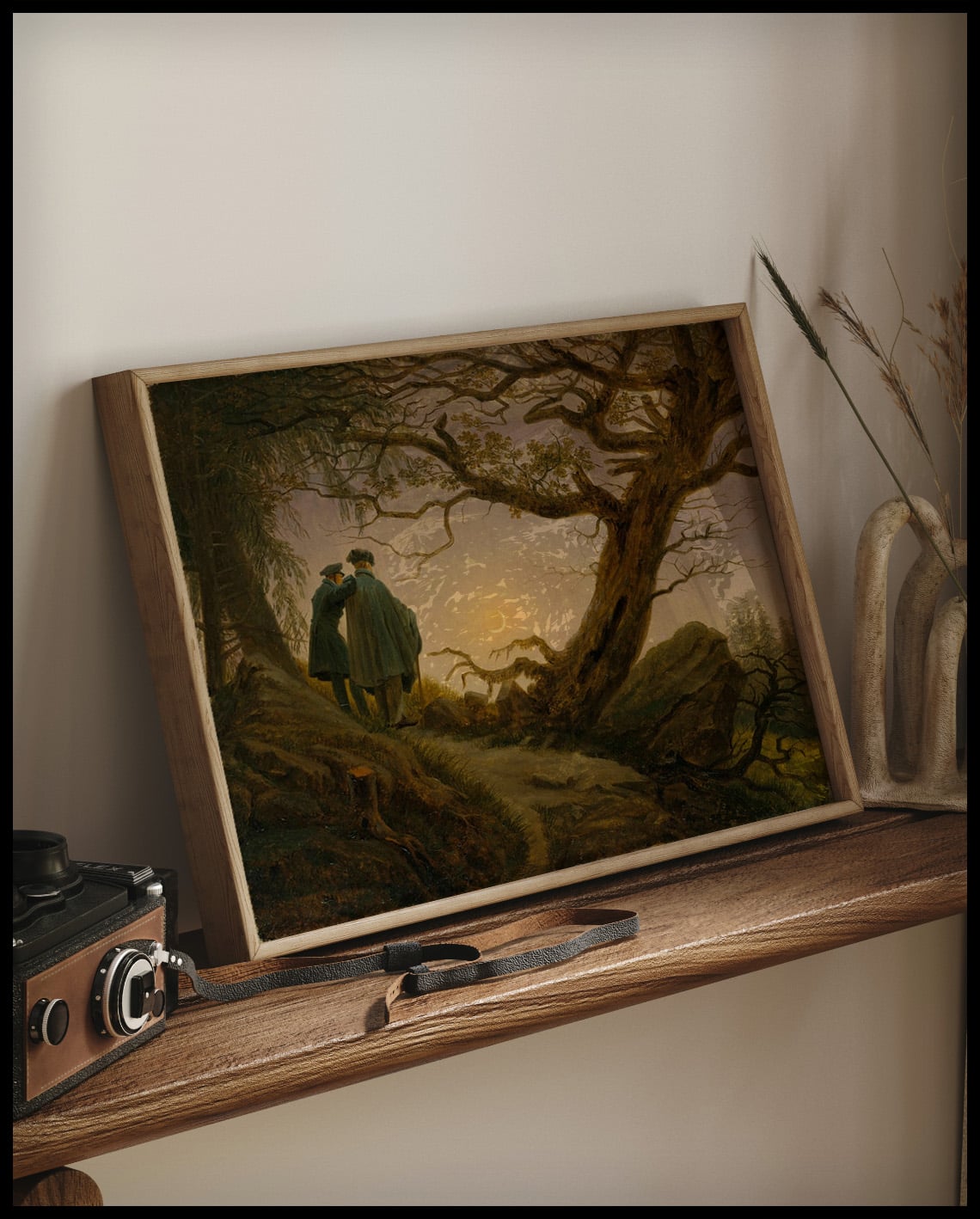 Ein gerahmter Kunstdruck von zwei Männern neben einem Baum die den Mond betrachten, auf einem Holzregal an die Wand angelehnt