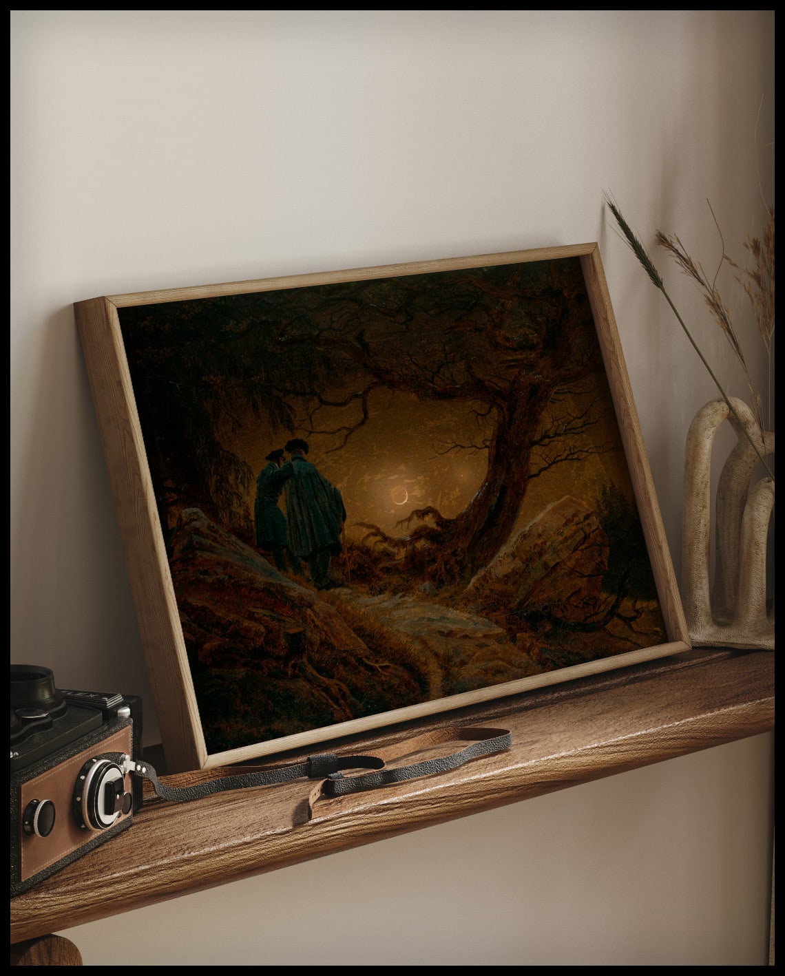 Ein gerahmter Kunstdruck von zwei Männern neben einem Baum die den Mond betrachten, auf einem Holzregal an die Wand angelehnt