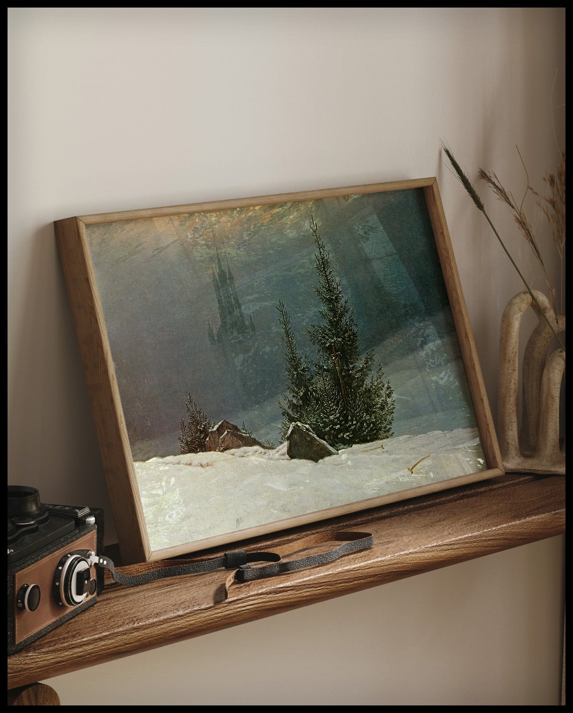 Ein gerahmter Kunstdruck von einer Kreuzigung und einer Kirche in einer Winterlandschaft, auf einem Holzregal an die Wand angelehnt