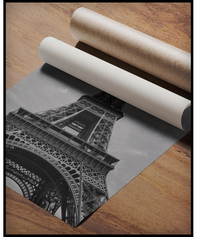 Ein Poster vom Eiffelturm in schwarz-weiß, gerollt auf einer Holzoberfläche liegend
