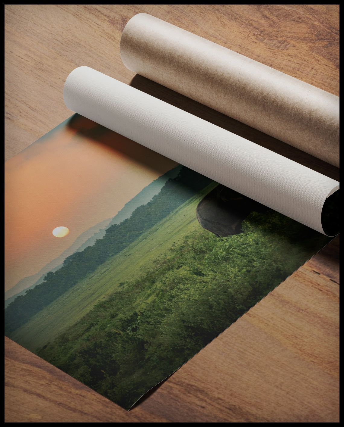 Ein Poster von zwei Elefanten bei Sonnenuntergang in Afrika, gerollt auf einer Holzoberfläche liegend