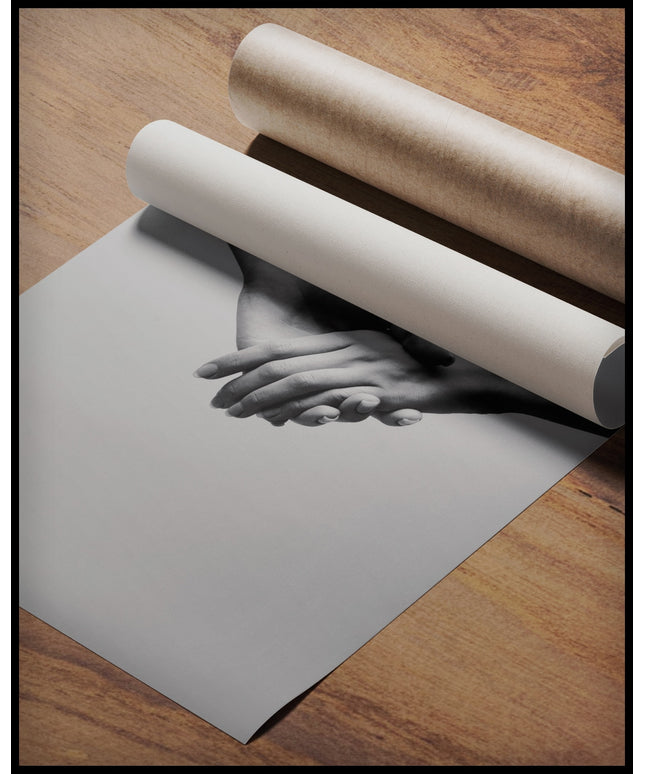 Ein Poster von zwei sich haltenden Händen in Schwarz-Weiß, gerollt auf einer Holzoberfläche liegend
