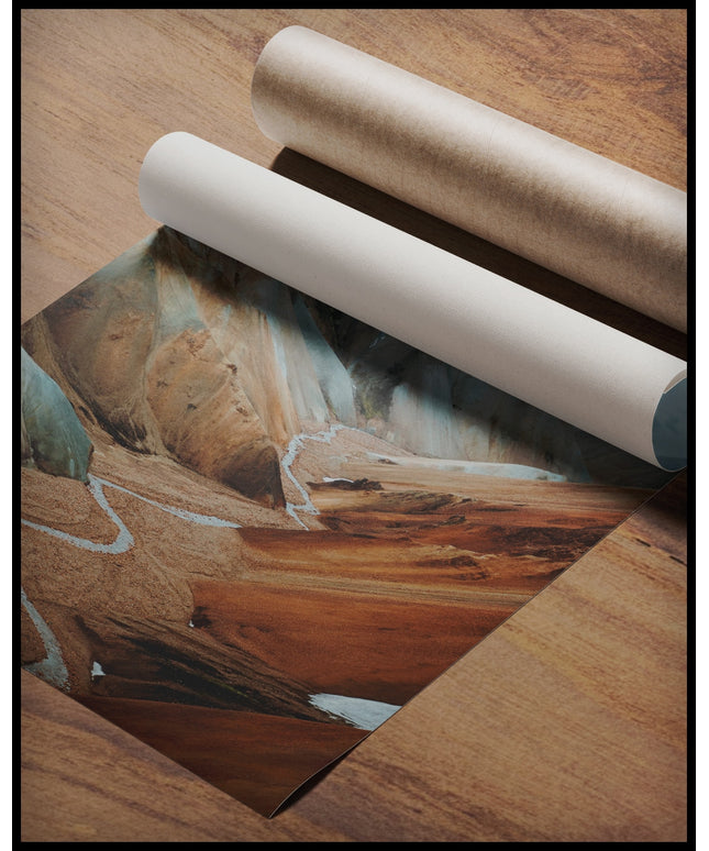 Ein Poster von einem Tal mit einem Fluss und orangenen Bergen, gerollt auf einer Holzoberfläche liegend