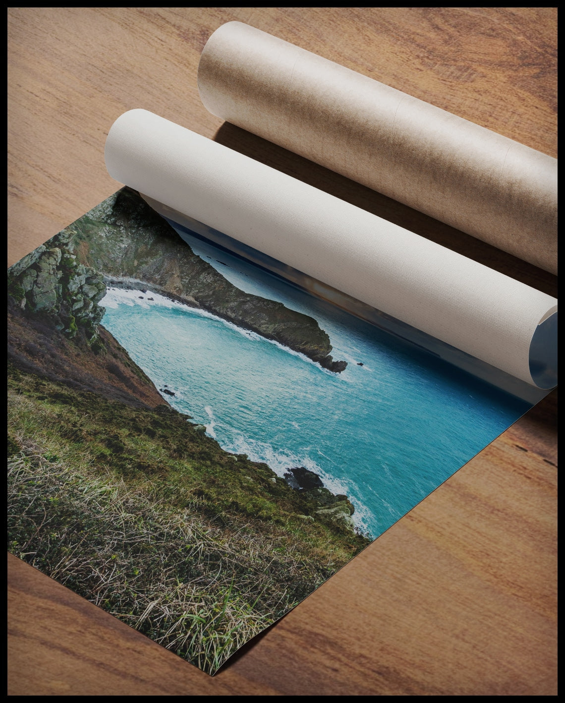 Ein Poster vom Blick einer Bucht über das blaue Meer, gerollt auf einer Holzoberfläche liegend