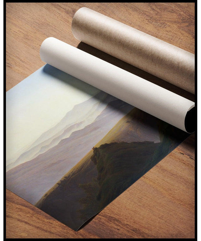 Ein Kunstdruck von einer weiten, nebligen Gebirgslandschaft am frühen Morgen, gerollt auf einer Holzoberfläche liegend