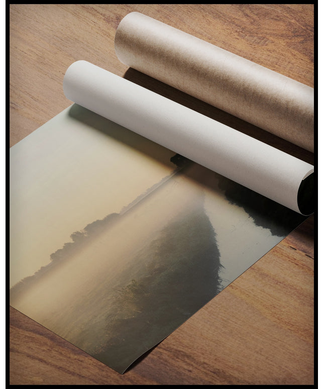 Ein Poster von einer nebligen Landschaft in den Niederlanden, mit einem Wasserkanal und einer Kirche im Hintergrund, gerollt auf einer Holzoberfläche liegend