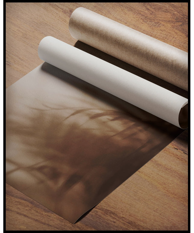 Ein Poster vom Schatten einzelner Palmenblätter auf einer beigefarbenen Häuserfassade, gerollt auf einer Holzoberfläche liegend