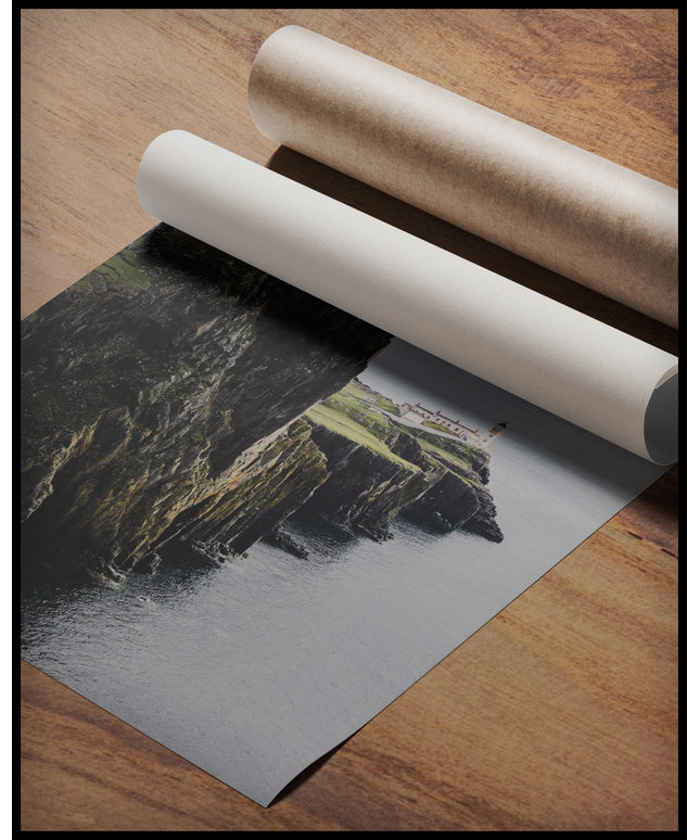 Ein Poster von einer kargen Klippe in Schottland mit einem Leuchtturm, gerollt auf einer Holzoberfläche liegend