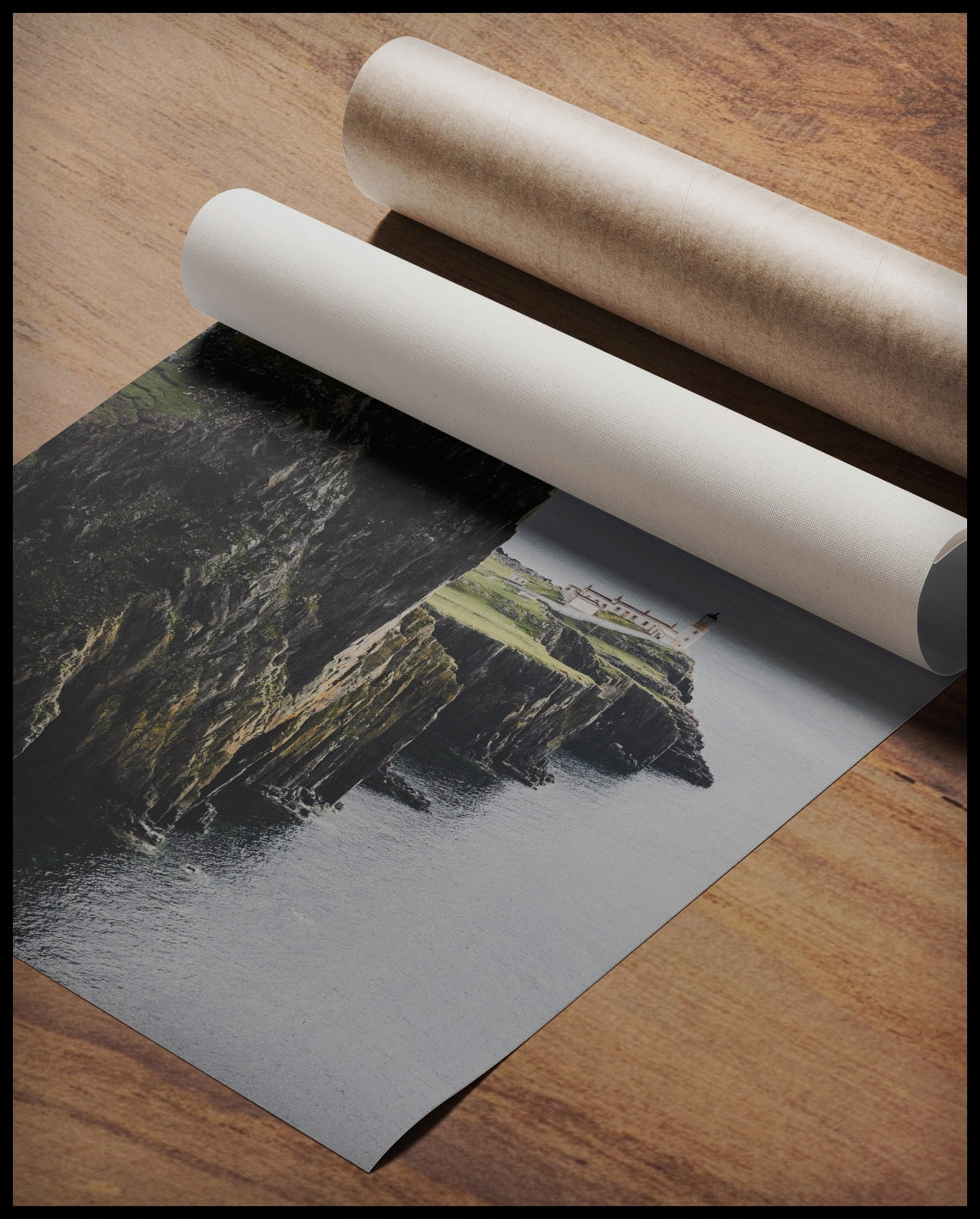 Ein Poster von einer kargen Klippe in Schottland mit einem Leuchtturm, gerollt auf einer Holzoberfläche liegend