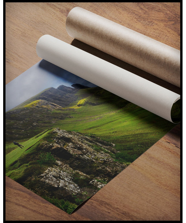 Ein Poster von grasbewachsenen Bergformationen auf der schottischen Insel Skye, gerollt auf einer Holzoberfläche liegend